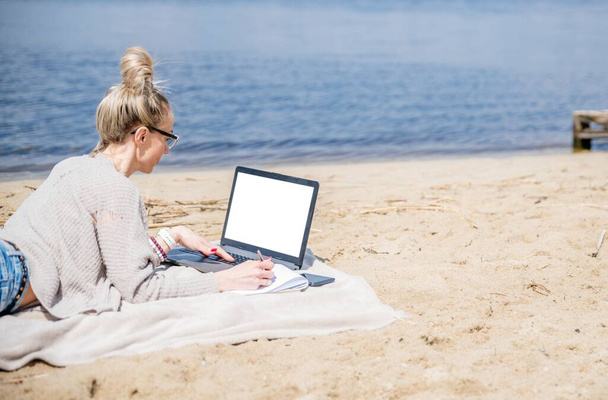 Una mujer trabajando en un lago, usando un portátil. Trabajo independiente. - Foto, imagen