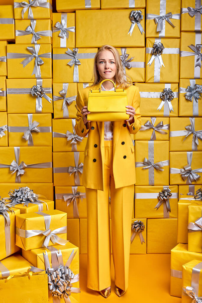 Scared blonde lady holding yellow handbag in hands and looking at camera - Foto, Imagem