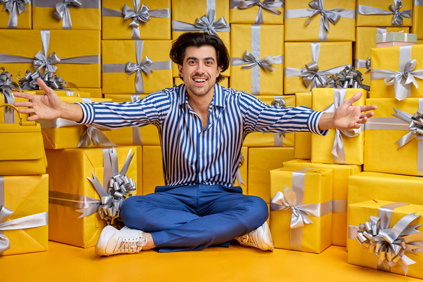 Happy handsome stylish man sitting among lot of presents gifts boxes - Foto, afbeelding