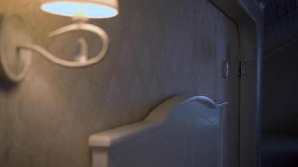Hoofd van het bed met een brandende lamp, de man draait op de tweede en gaat naar bed - Video