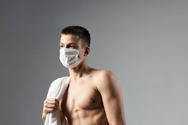 cute guy in medical mask naked shoulders workout towels gym - Foto, afbeelding