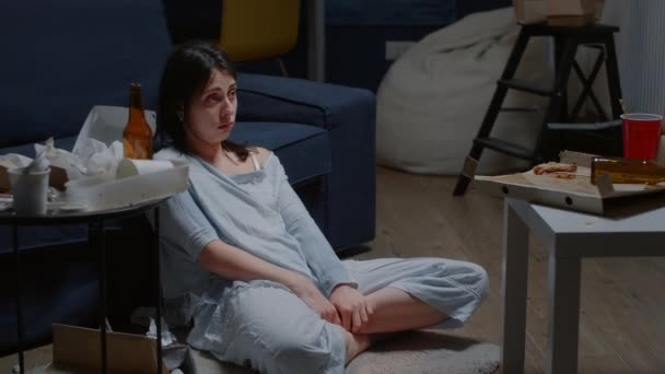 Θλιβερή νεαρή γυναίκα που κάθεται μόνη στο πάτωμα κλαίγοντας κοιτάζοντας την κάμερα - Πλάνα, βίντεο