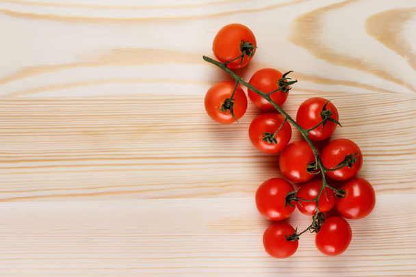 Pomidory wiśniowe na winorośli. Drewniane tło z miejscem na tekst - Zdjęcie, obraz