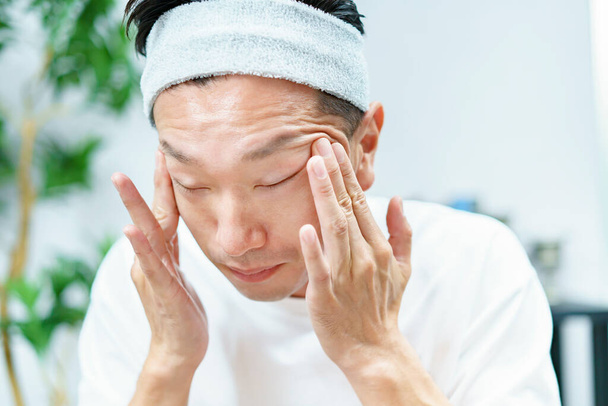 Hombres aplicando crema hidratante en su cara en la habitación - Foto, Imagen