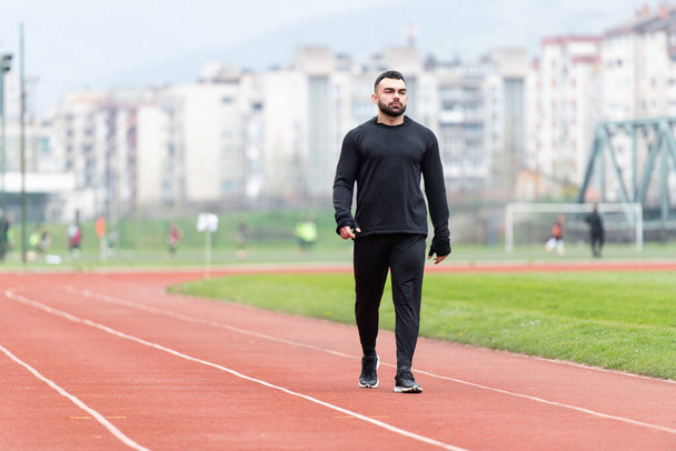 Portrait of Athletic Man on Running Track Getting Ready to Start Run - Foto, imagen