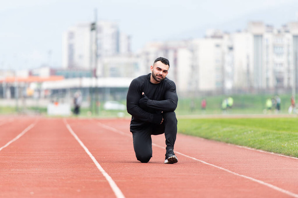 Young Athlete Man Relax and Strech Ready for Run at Athletics Race Track on Stadium Showing Thumbs Up - Φωτογραφία, εικόνα