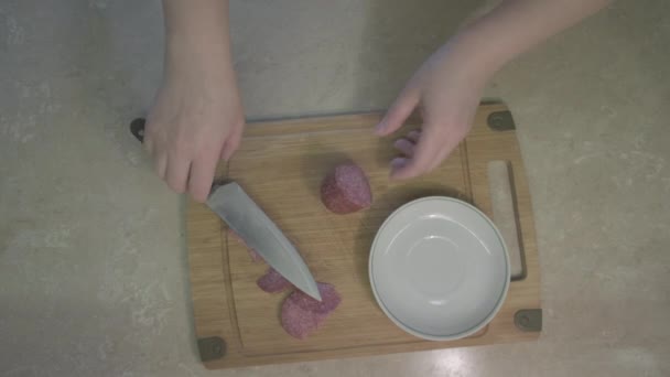 Man crookedly cuts sausage. Woman shoos it away, starts slicing product evenly - Footage, Video