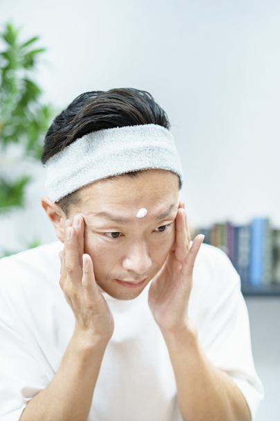 Hombres aplicando crema hidratante en su cara en la habitación - Foto, Imagen