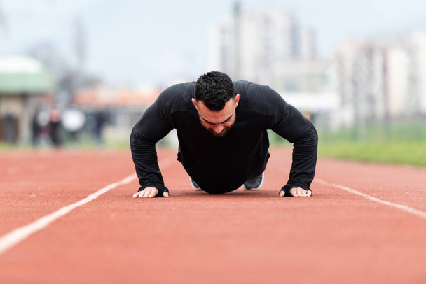 Handsome Young Man Doing Pushups on a Track - Fotoğraf, Görsel