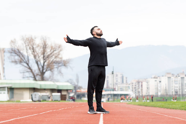 Young Athlete Man Relax and Strech Ready for Run at Athletics Race Track on Stadium - 写真・画像