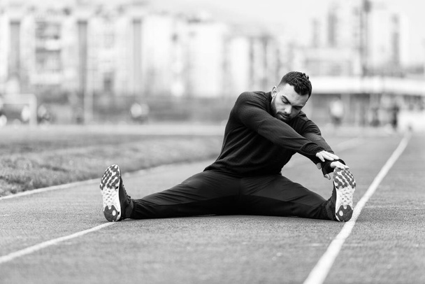 Portrét fit a sportovní mladý muž dělá roztahování v parku - Fotografie, Obrázek