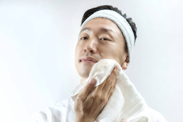 Γιαπωνέζος μεσήλικας σκουπίζει το πρόσωπό του με πετσέτα.  - Φωτογραφία, εικόνα