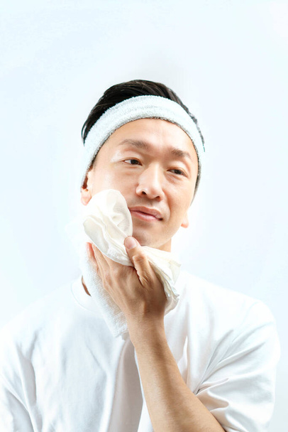 Japonés de mediana edad hombre limpiándose la cara con una toalla  - Foto, imagen