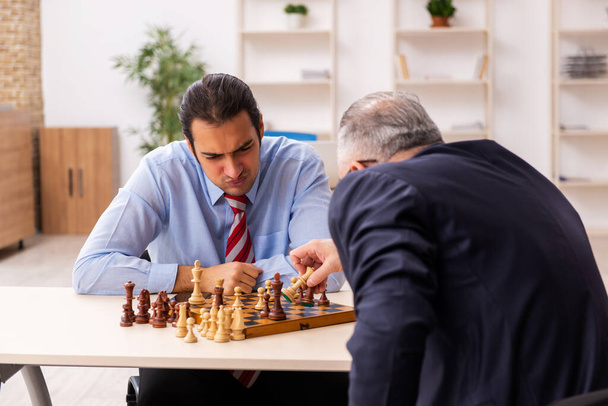 Два бизнесмена играют в шахматы в офисе - Фото, изображение