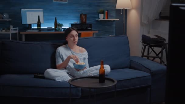 Femme manger du pop-corn et regarder une série intéressante à la télévision - Séquence, vidéo