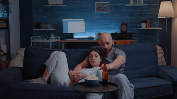 Boldog pár otthon pihentető kanapén néz kedvenc TV-műsorok - Felvétel, videó
