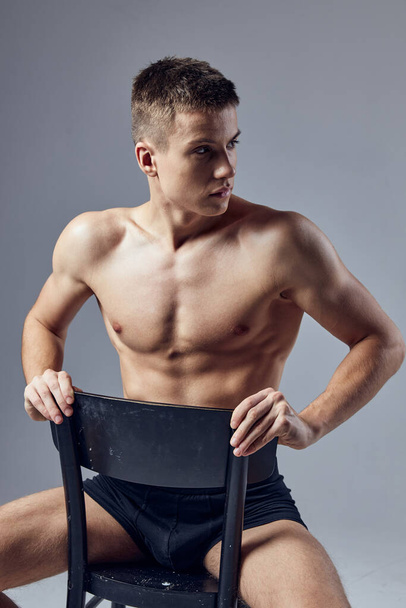 handsome man athletic physique sitting on chair inflated body isolated background - Zdjęcie, obraz