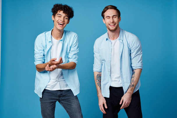 Lockenkopf im Hemd und blonder Mann auf blauem Hintergrund plaudern Freunde beschnitten Ansicht - Foto, Bild