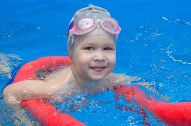 мальчик в плавательных очках и плавательной шапке в бассейне - Фото, изображение