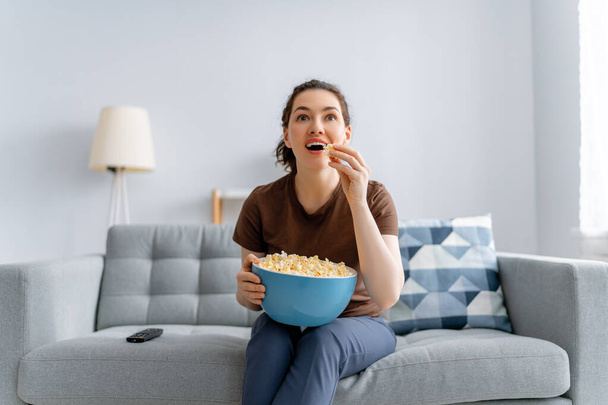 Young woman watching  TV, movies with popcorn. Girl spending time at home. - Foto, Imagen