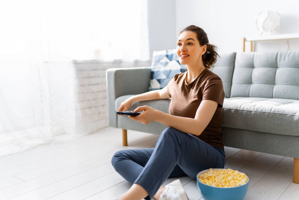 Young woman watching  TV, movies with popcorn. Girl spending time at home. - Foto, Bild