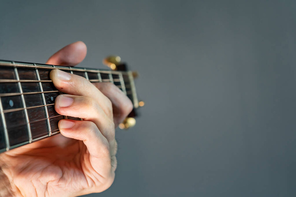 Χέρι κρατώντας χορδή κιθάρας με χώρο αντίγραφο στα δεξιά - Φωτογραφία, εικόνα