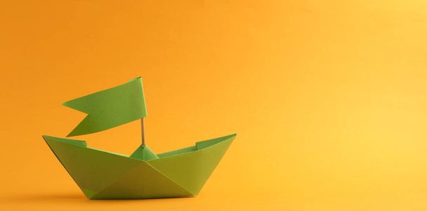 Πράσινο χάρτινο σκάφος σε κίτρινο φόντο με χώρο για κείμενο - Φωτογραφία, εικόνα