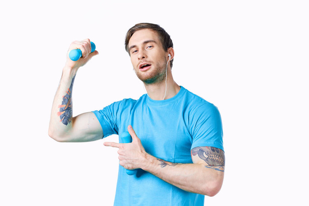 man met opgeblazen armspieren toont vinger aan de zijkant en halters bodybuilder fitness - Foto, afbeelding
