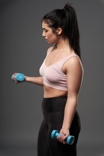 Happy plus size hispanic woman doing fitness exercises with small dumbbells - Фото, зображення