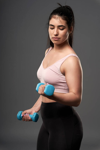 Happy plus size hispanic woman doing fitness exercises with small dumbbells - Foto, afbeelding