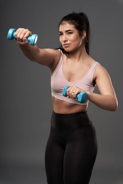 Happy plus size hispanic woman doing fitness exercises with small dumbbells - Foto, immagini