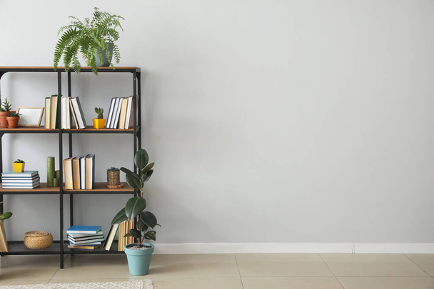 Shelf unit with books near light wall - Φωτογραφία, εικόνα