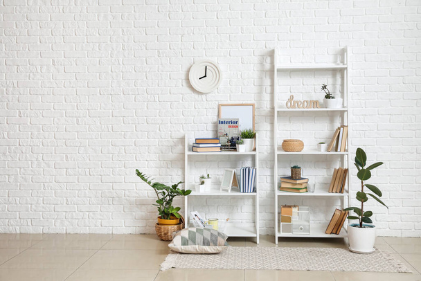 Shelf units with books and decor near light brick wall - Photo, Image