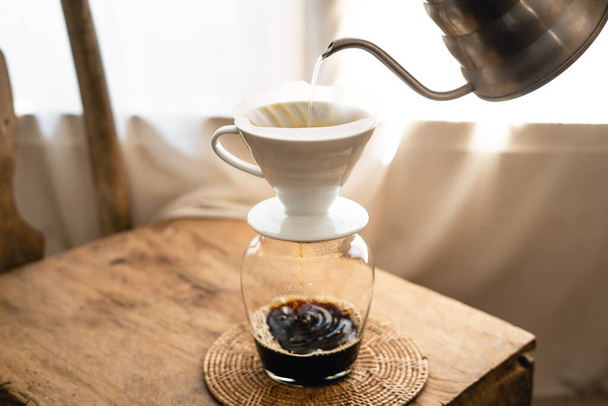 Man adding hot water into coffee dripper above glass jar. - Photo, Image