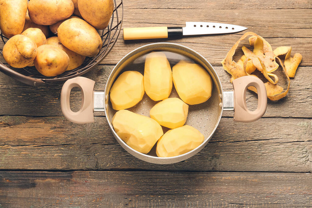 Cooking pot with peeled potatoes on wooden background - Foto, Imagen
