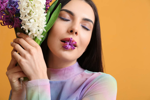 Hermosa mujer joven con flores de jacinto sobre fondo de color - Foto, Imagen