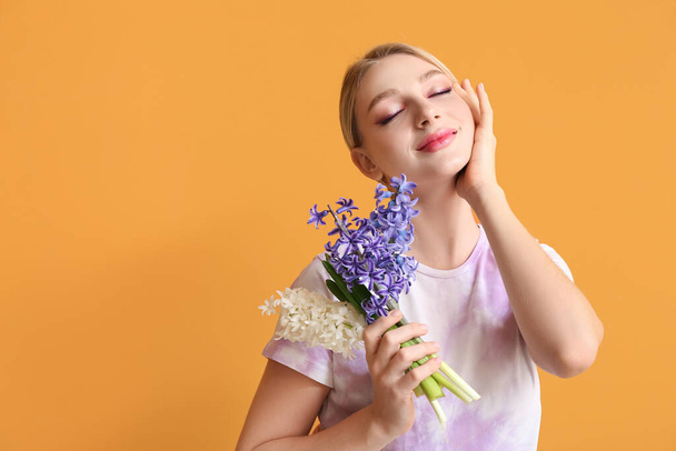 Beautiful young woman with hyacinth flowers on color background - Photo, image