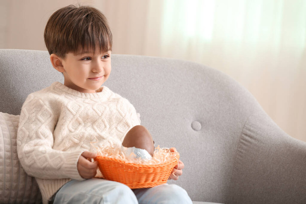 Cute little boy with chocolate Easter egg at home - Foto, Imagen