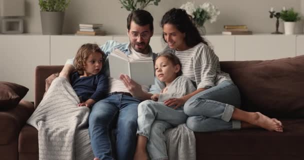 Happy caring young parents reading book to children. - Video