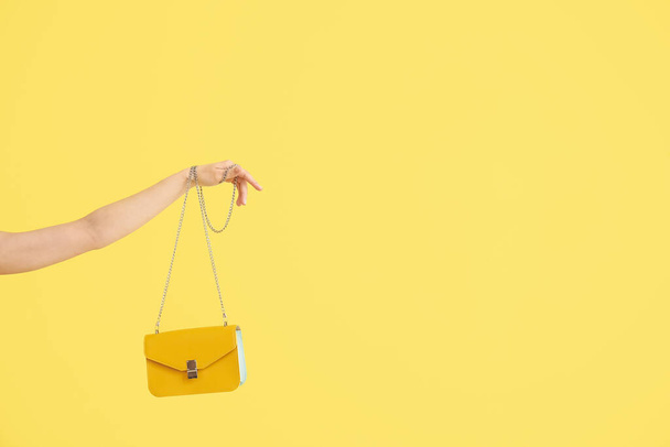 Female hand with stylish bag on yellow background - Foto, imagen