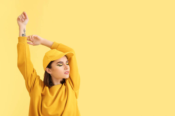 Stylish young woman on yellow background - Foto, imagen