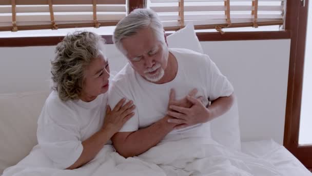 Ασιατικό ηλικιωμένο ζευγάρι στο κρεβάτι, πόνους στην καρδιά λόγω καρδιακής νόσου. - Πλάνα, βίντεο