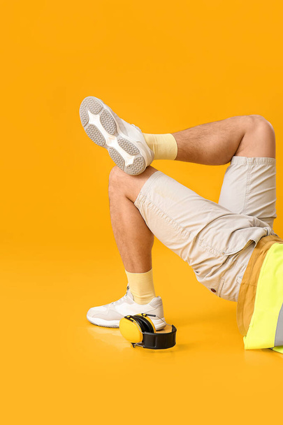 Leżący pracownik ze słuchawkami na żółtym tle - Zdjęcie, obraz
