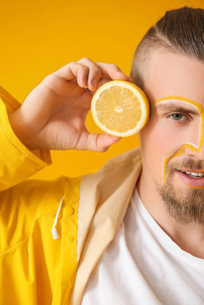 Stijlvolle jongeman met citroen op gele achtergrond - Foto, afbeelding