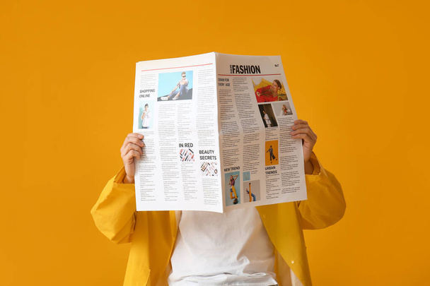 Stylish young man with newspaper on yellow background - Фото, зображення