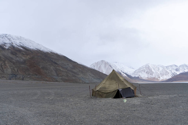 Индийская военная палатка в заброшенном месте в Ладакхе с красивыми снежными горами на заднем плане. - Фото, изображение