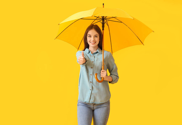 Stílusos fiatal nő esernyő mutatja hüvelykujj-up a színes háttér - Fotó, kép