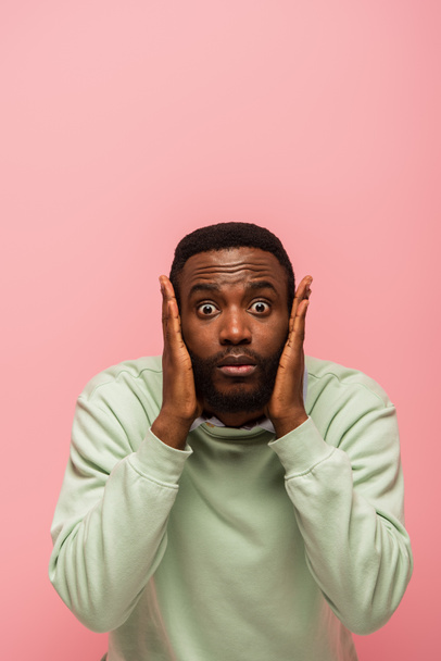 Excited african american man with hands near face looking at camera isolated on pink  - Фото, зображення
