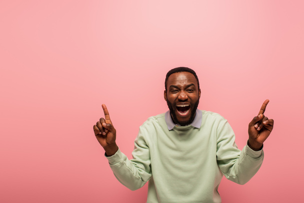 Excited african american man pointing with fingers isolated on pink  - Foto, immagini