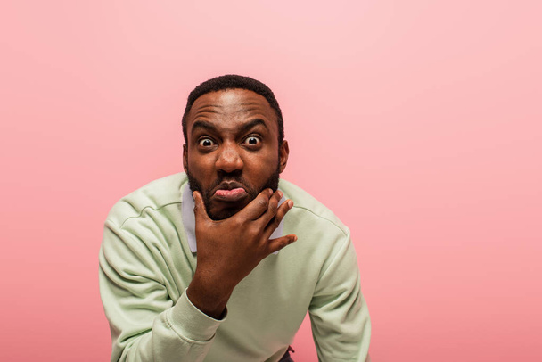 African american man grimacing at camera isolated on pink  - Фото, зображення